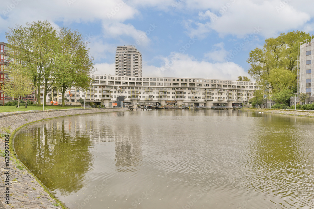 some buildings on the side of a body of water with trees in the background and clouds in the blue sky