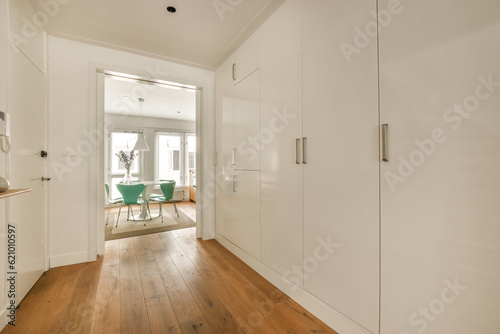 a room with white walls and wood flooring in the middle of the room there is an open door leading to another room
