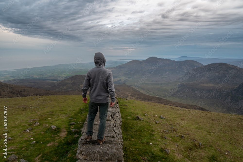 Panoramic view of typical Irish landscape, fields, sea in background. Picture taken from the top of the mountain. Hiker enjoing view after sunset