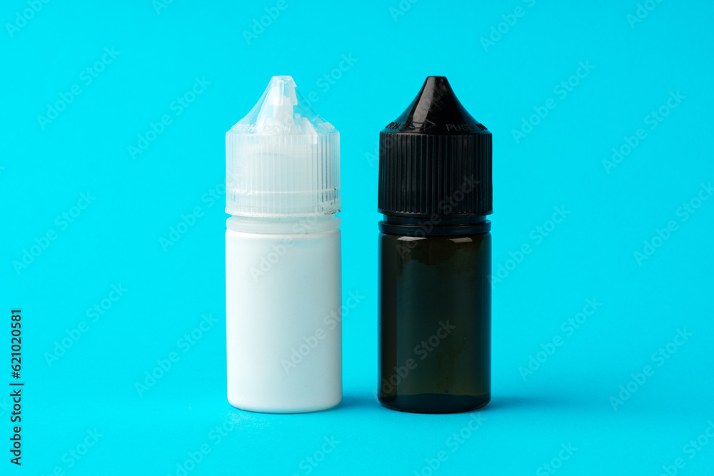 Electronic cigarettes liquid bottles on blue background Electronic cigarettes liquid bottles on blue background