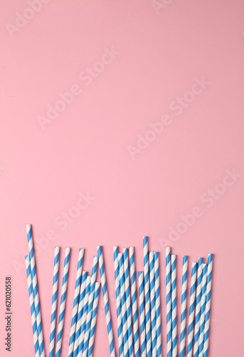 Blue paper straws on pink pastel background. Party, birthday accessories