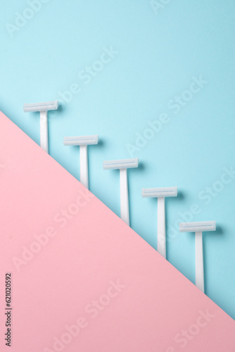 Disposable white plastic razors on pink pastel background. Creative layout