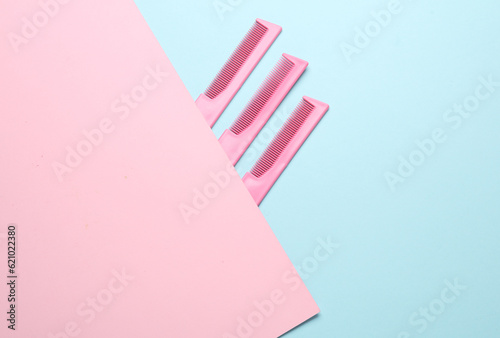 Pink plastic combs on a blue pink background. Beauty and fashion minimalism still life