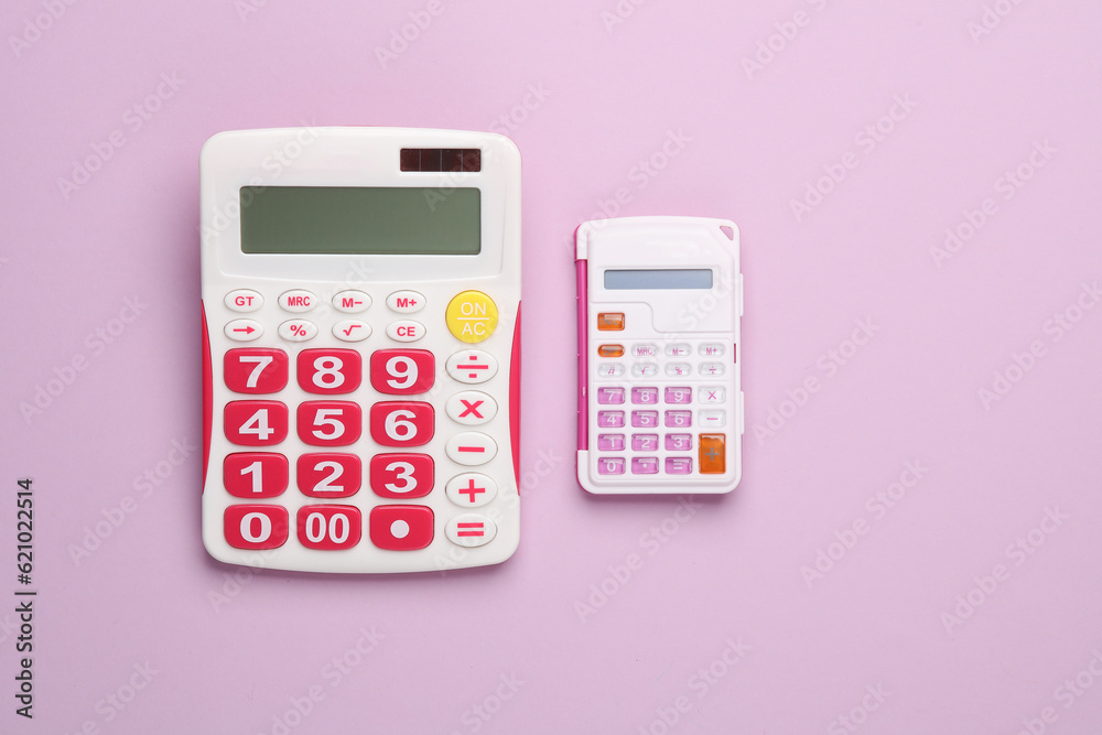 Big and small calculators on pink background. Top view Big and small calculators on pink background. Top view