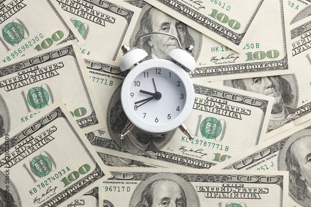 Alarm clock on hundred dollar bills. Time is money Alarm clock on hundred dollar bills. Time is money