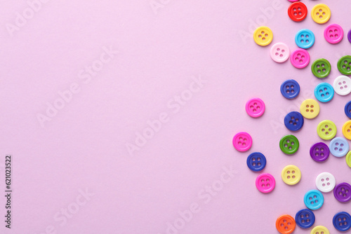 Many colored plastic buttons on a pink background. Copy space