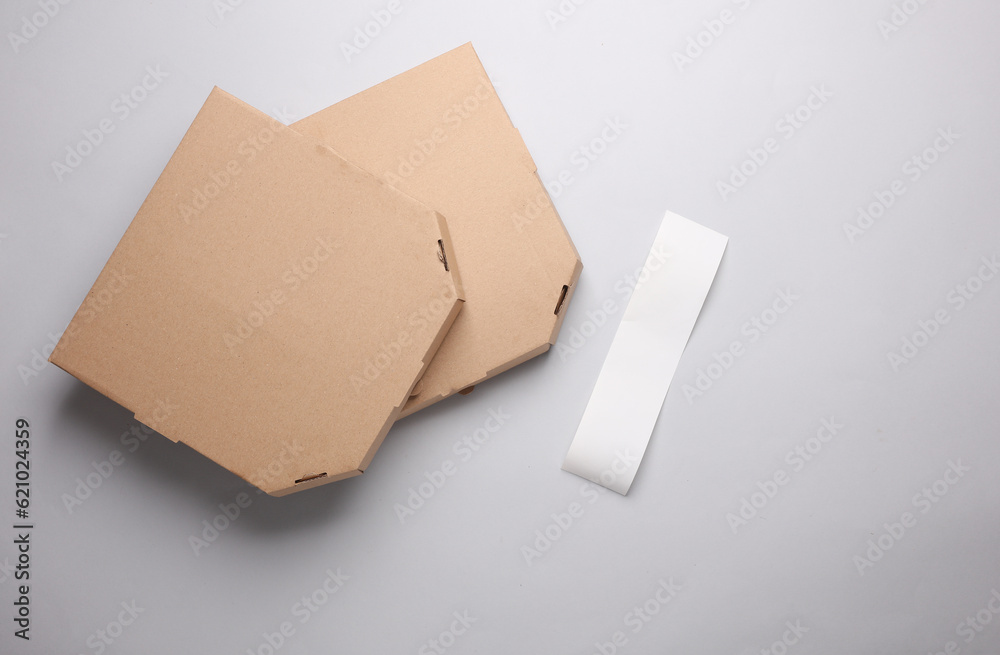 Two craft cardboard pizza boxes and check tape on gray background. Template for design. Top view Two craft cardboard pizza boxes and check tape on gray background. Template for design. Top view