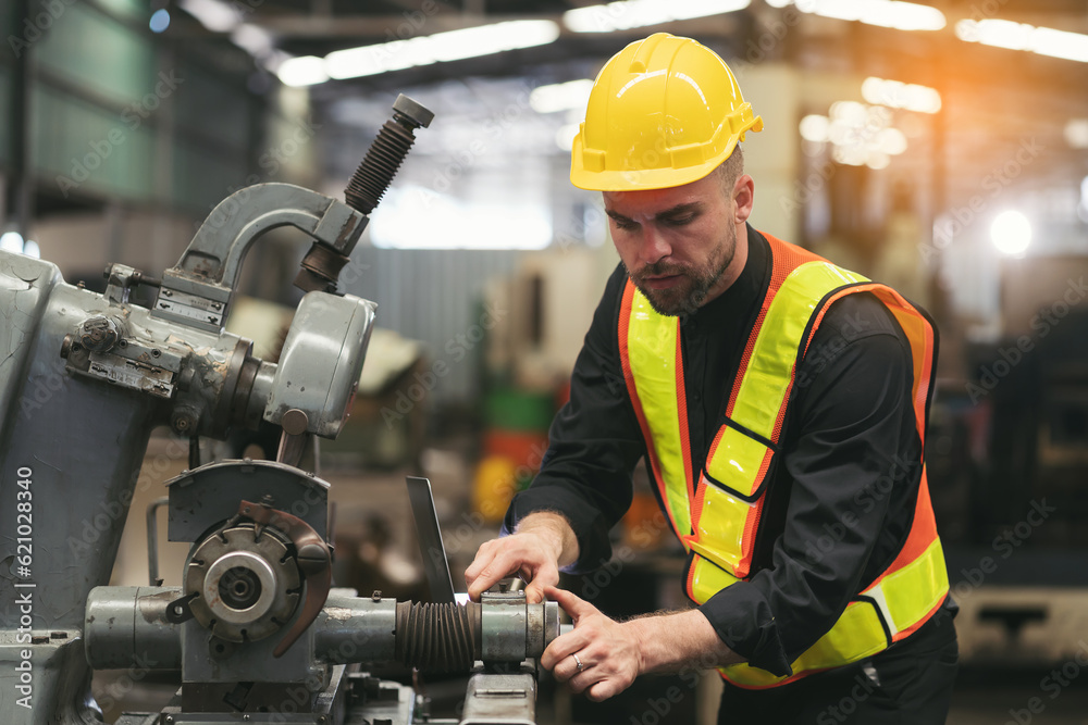 Male engineer worker working and inspecting parts quality of lathe machine in industry factory, wearing safety uniform, helmet. Male technician worker maintenance parts of machine in workshop