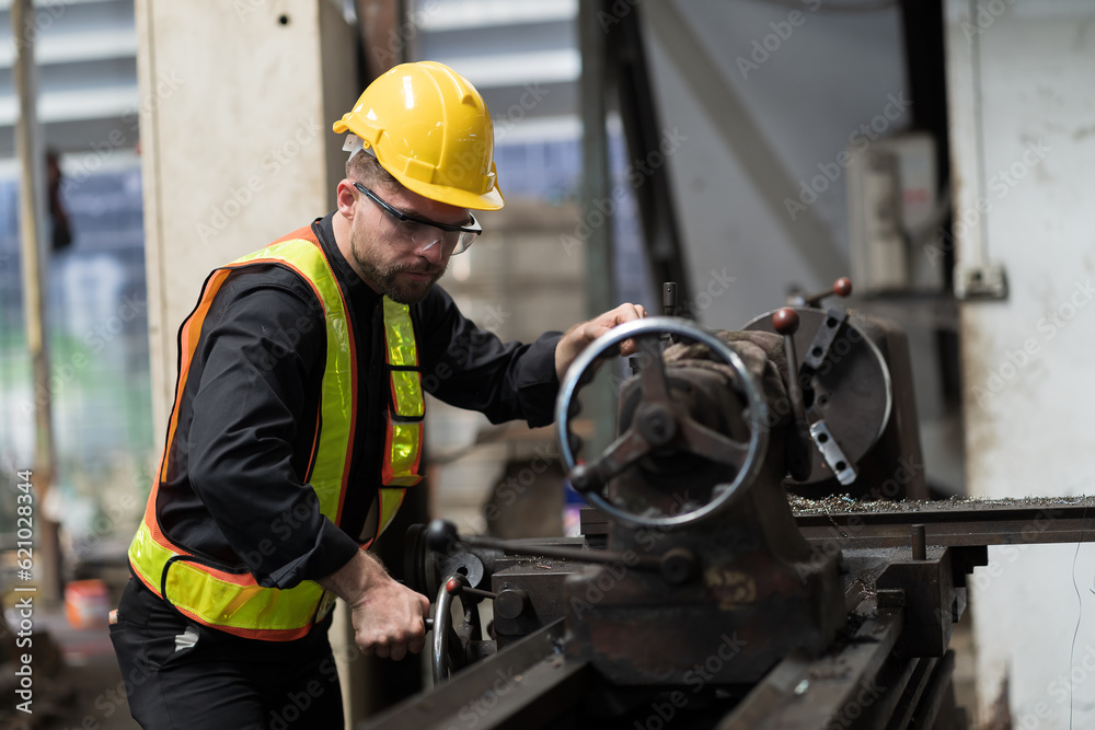 Male engineer worker working and inspecting parts quality of lathe machine in industry factory, wearing safety uniform, helmet. Male technician worker maintenance parts of machine in workshop Male engineer worker working and inspecting parts quality of lathe machine in industry factory, wearing safety uniform, helmet. Male technician worker maintenance parts of machine in workshop