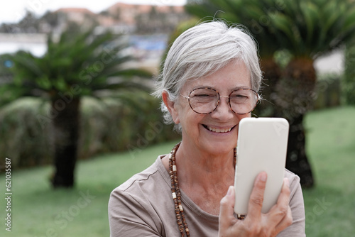 Video call concept. Portrait of happy senior woman enjoying video chat using mobile phone. Headshot of elderly female with eyeglasses in virtual connection with family or friends