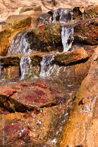 Water running over rocks with red leaves on a spring day at a lake near Kaiserslautern, Germany in the Palatinate Forest. photo