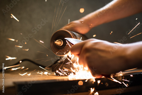 Fototapeta Close-up of men's hands sharpening an axe on an electric sharpener