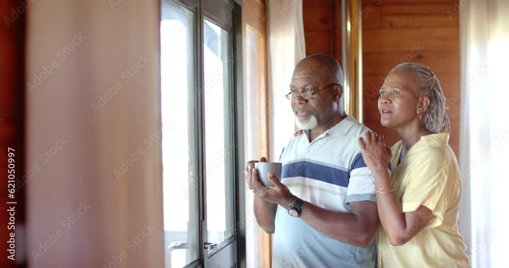 Senior african american couple talking and looking out window at home, slow motion Senior african american couple talking and looking out window at home, slow motion
