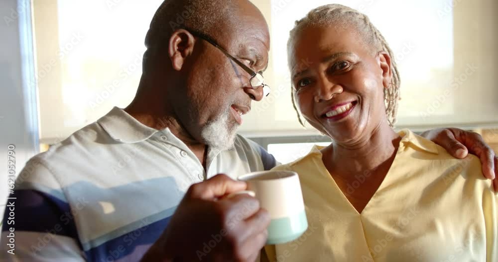 Happy senior african american couple drinking coffee and embracing in kitchen, slow motion Happy senior african american couple drinking coffee and embracing in kitchen, slow motion