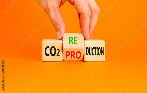 CO2 production or reduction symbol. Concept word CO2 production reductionon a wooden block on a beautiful orange background. Businessman hand. Business ecological and CO2 changes concept. Copy space. photo