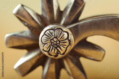 Engraving on western spur rowel metal closeup with blurred background for cowboy concept.