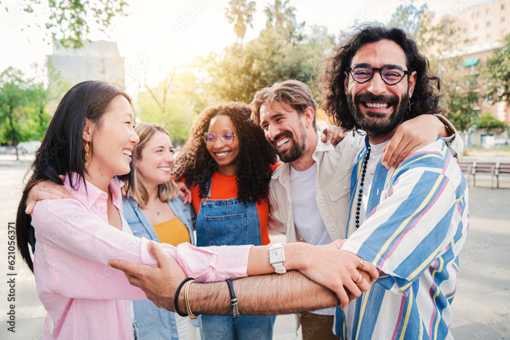 Group of joyful young adult friends embracing each others on a social gathering outdoors, having fun and enjoying standing in a circle. Strong friendship multiracial people hugging showing team unity Group of joyful young adult friends embracing each others on a social gathering outdoors, having fun and enjoying standing in a circle. Strong friendship multiracial people hugging showing team unity