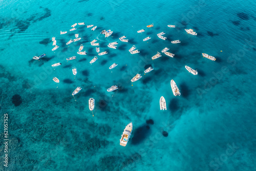 Aerial view of motorboats in shape of the heart on blue sea at sunset in summer. Travel in Sardinia, Italy. Drone view from above of speed boats, yachts, ocean, transparent azure water. Tropical