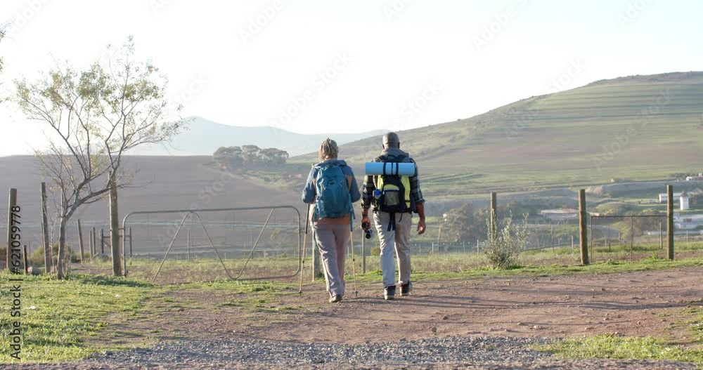 Senior african american couple with backpacks walking in sunny nature, slow motion
