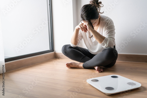 Sad woman with fat upset bored of dieting Weight loss fail  Fat diet and scale sad asian woman on weight scale at home weight control