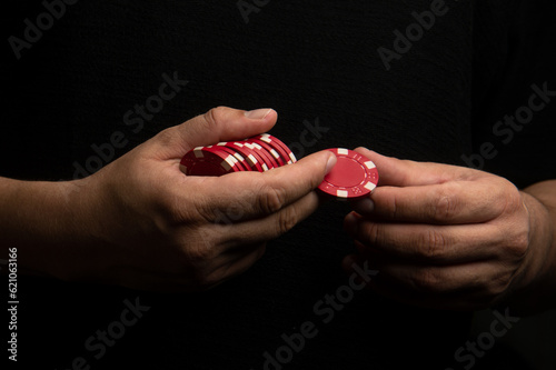 Poker chips in male hands. A man holds gambling chips on a black background.