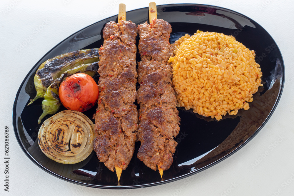 Grilled Turkish Adana, Urfa Kebab with grilled vegetables, onion and rice on plate. Adana durum. Grilled Turkish Adana, Urfa Kebab with grilled vegetables, onion and rice on plate. Adana durum.