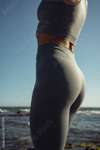 beautiful athletic female figure in a gray tracksuit on the background of the sea