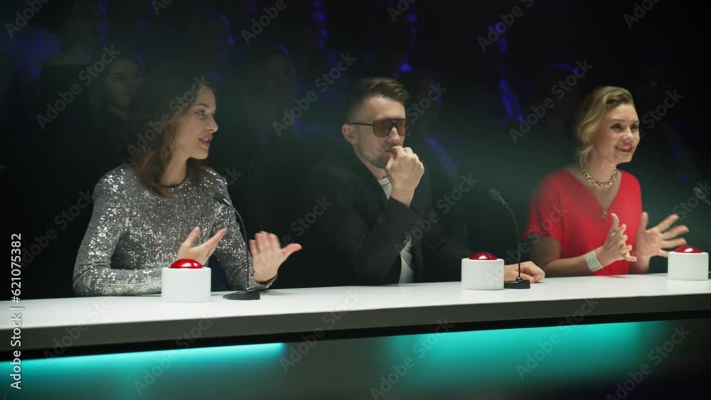 Portrait of celebrity judges enjoying the audition performed by talent on stage during the recording of a broadcast TV television talent show 