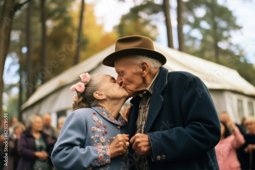 Elderly couple kissing celebrating their annibersary with their friends and family.