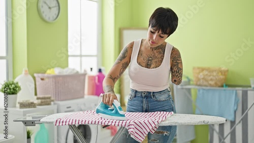 Hispanic woman with amputee arm ironing clothes at laundry room