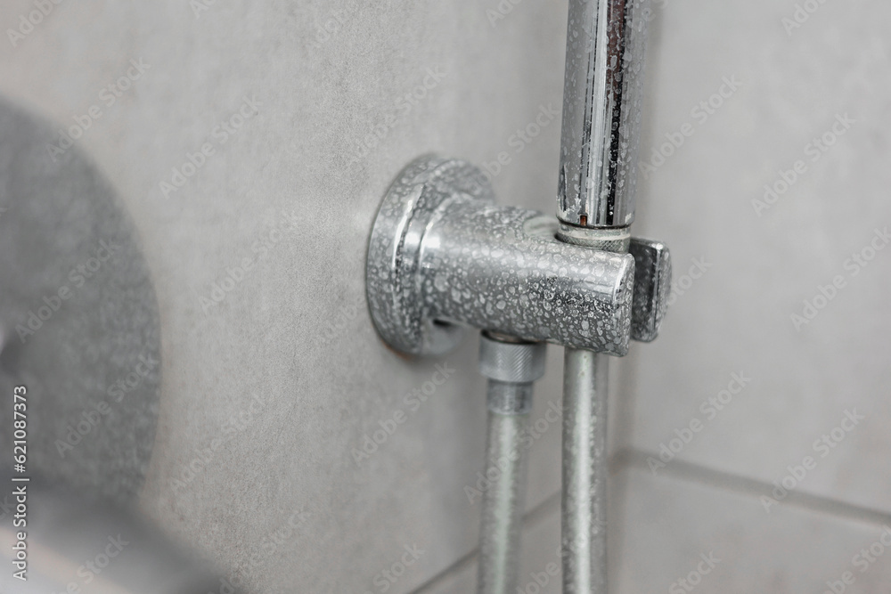 Dirty calcified shower mixer tap, faucet with limescale on it, plaque from hard water, Chrome plated shower, close up photo. Bathroom with grey tiles interior. Dirty calcified shower mixer tap, faucet with limescale on it, plaque from hard water, Chrome plated shower, close up photo. Bathroom with grey tiles interior.