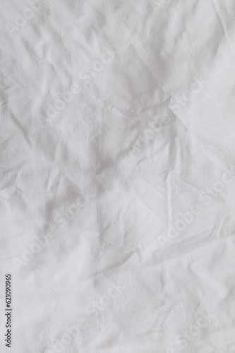 Closeup of a messy bedding sheet. Crumpled bedding sheet for background and decoration. Minimal background and texture concept. Flat lay, top of view. Copy space for text.