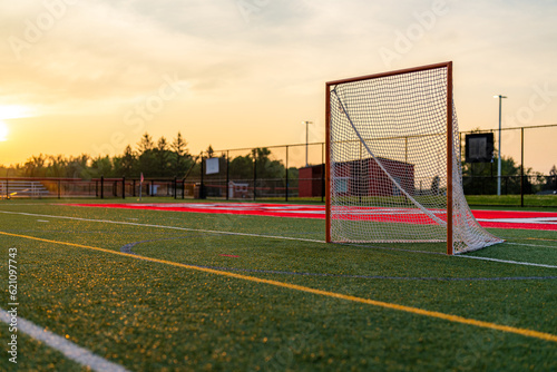 Dramatic late afternoon photo of a lacrosse goal on a synthetic turf field.	 photo
