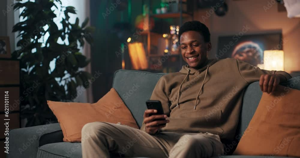 African Lifestyle Blogger African man on a comfortable couch, capturing moments of his daily life with a cellphone, sharing tips and inspiring others as a lifestyle blogger.