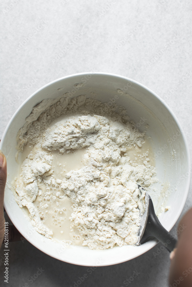 Partially mixed bread dough, flour being folded into water, process of making focaccia Partially mixed bread dough, flour being folded into water, process of making focaccia
