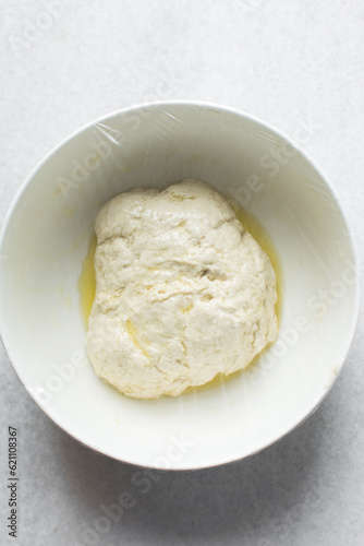 bread dough coated in olive oil, bread dough left to rise in white mixing bowl, process of making bread