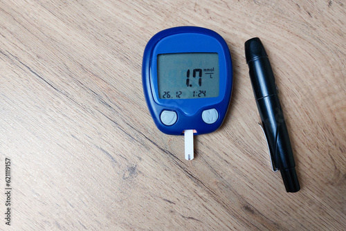 The device for measuring blood sugar lies on the table. Very low blood sugar (hypoglycemia). Copy space. photo