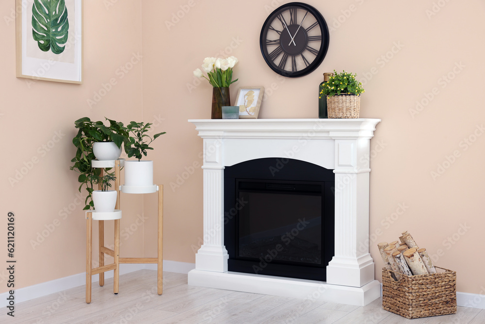 Stylish fireplace near potted plants and firewood in cosy living room Stylish fireplace near potted plants and firewood in cosy living room