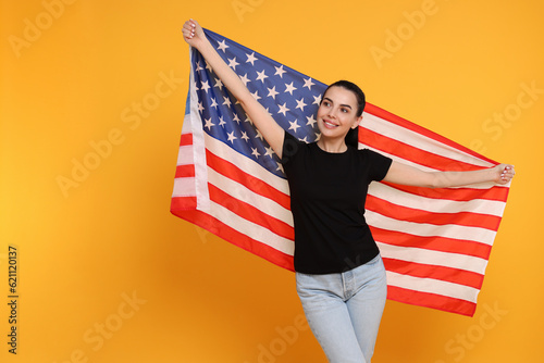 4th of July - Independence Day of USA. Happy woman with American flag on yellow background, space for text