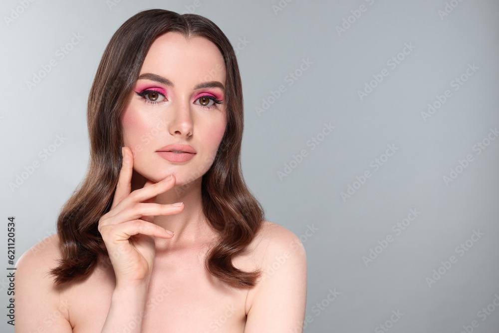 Portrait of beautiful young woman with makeup and gorgeous hair styling on light grey background. Space for text Portrait of beautiful young woman with makeup and gorgeous hair styling on light grey background. Space for text