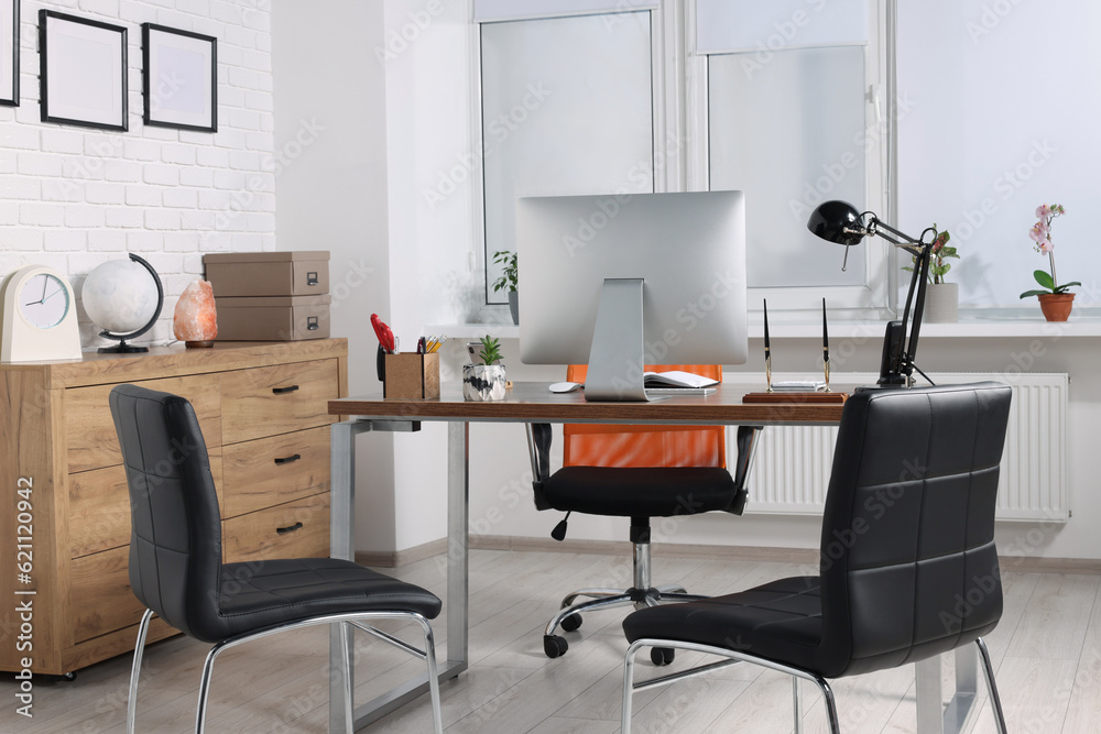 Stylish director's workplace with comfortable desk, computer and chairs for visitors in office. Interior design Stylish director's workplace with comfortable desk, computer and chairs for visitors in office. Interior design