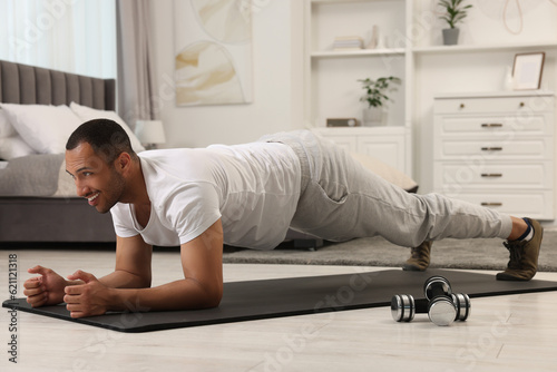 Man doing morning exercise on fitness mat at home