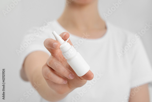 Woman holding nasal spray indoors, closeup view