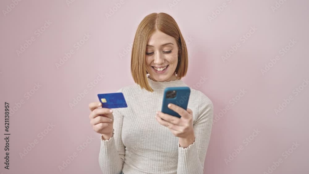 Young blonde woman shopping with smartphone and credit card over isolated pink background