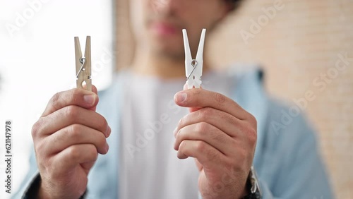 Wallpaper Mural Young latin man choosing wooden or plastic clothespin at home Torontodigital.ca