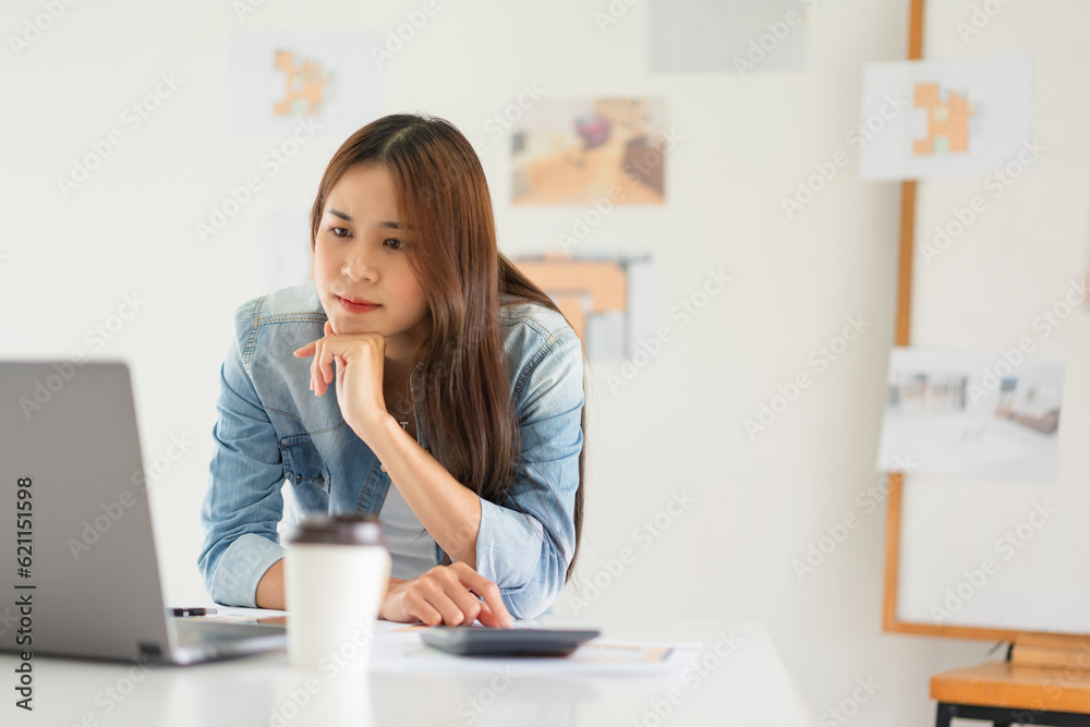 Construction design concept, Female architect use calculator and looks house plan project on laptop Construction design concept, Female architect use calculator and looks house plan project on laptop