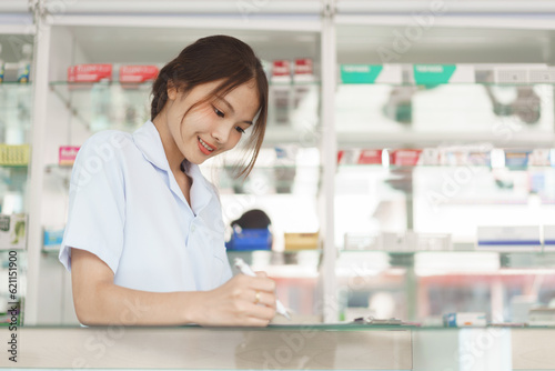 Medicine and health concept, Female pharmacist is checking stock medicine and writing on clipboard