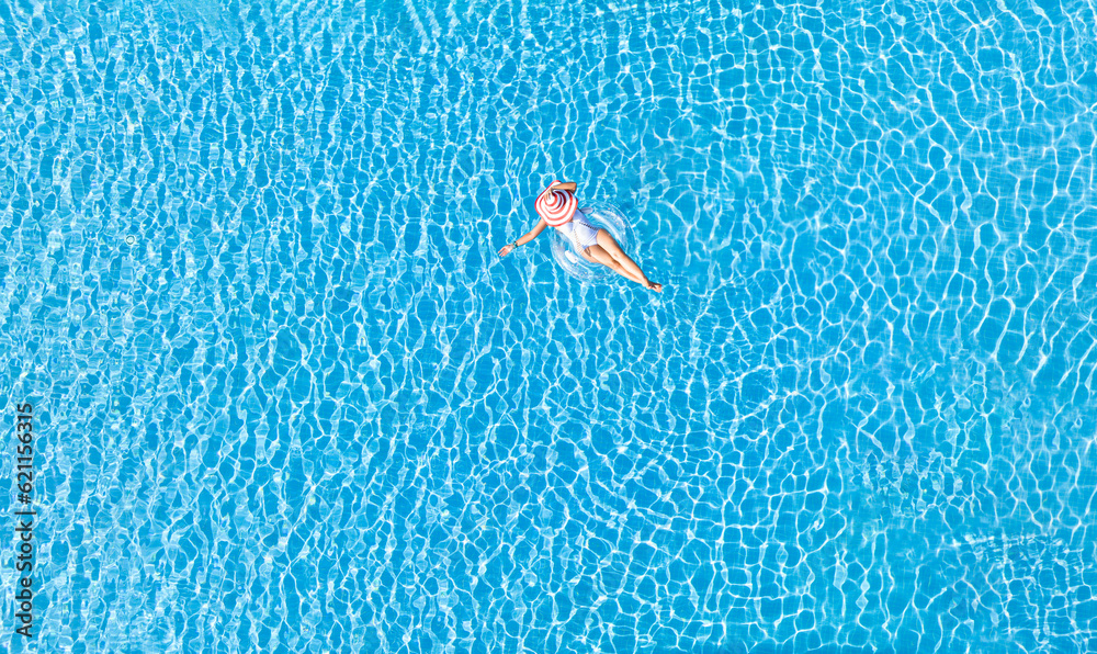 Aerial view with woman in bikini sunbathing as laying on swim ring as ...