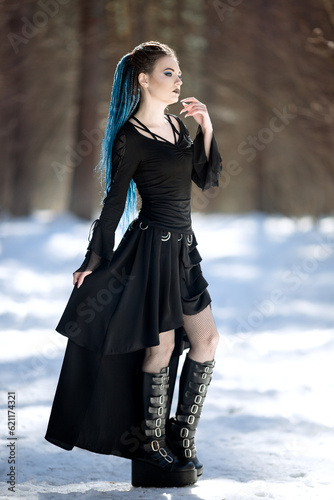 girl in black dress with blue hair dreadlocks wear gothic shoes