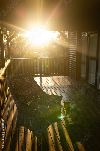 Vertical image of balcony of log cabin with armchair and mug of coffee on sunny day